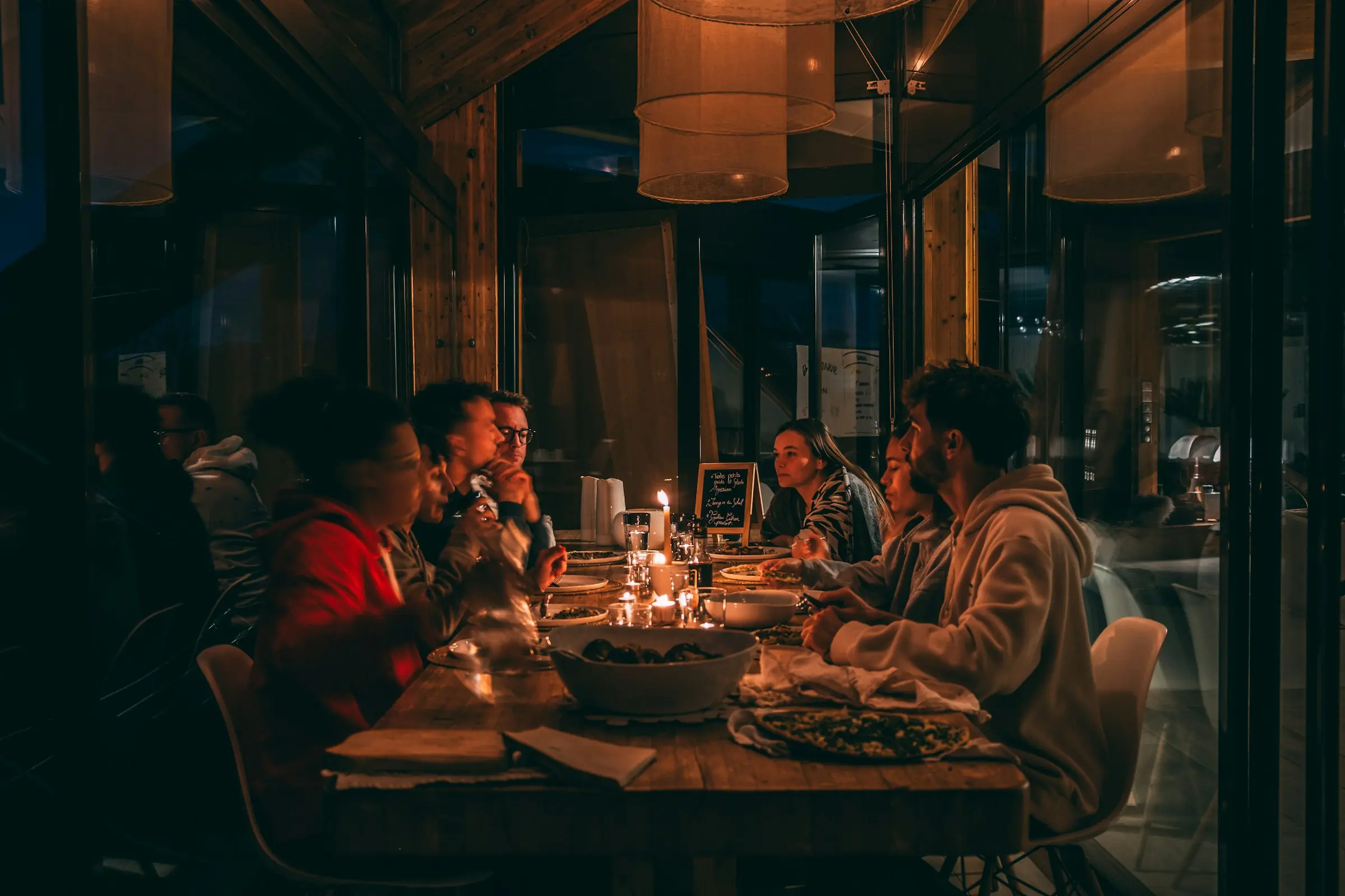Friends around a candlelit wooden table in a warm, wood-panelled restaurant.